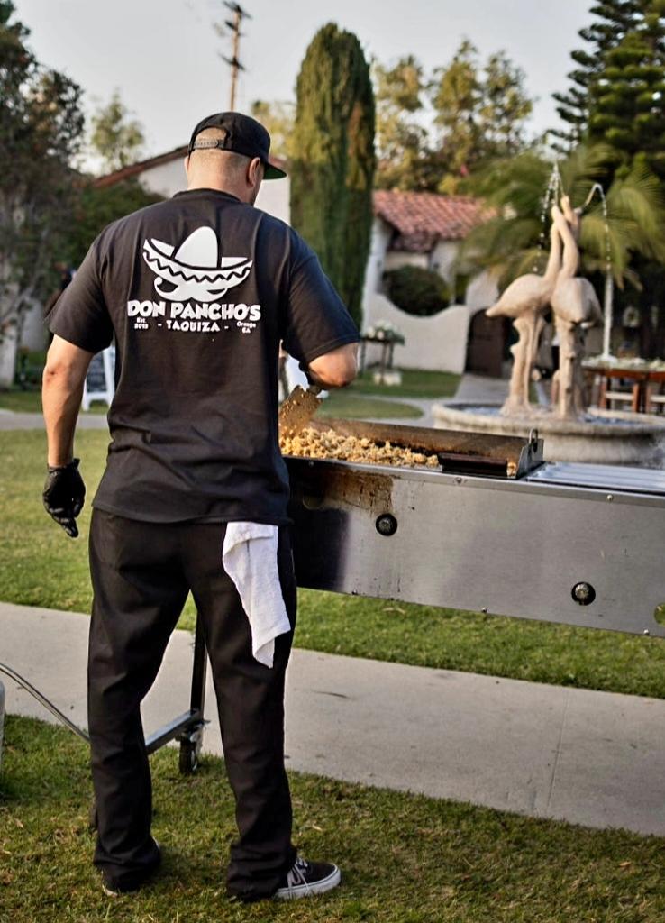 man standing at grill with a don pancho's shirt on